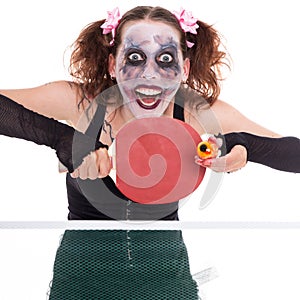 Scary female clown is playing ping-pong