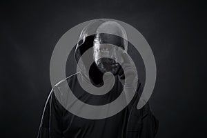 Scary figure in hooded cloak with mask in hand