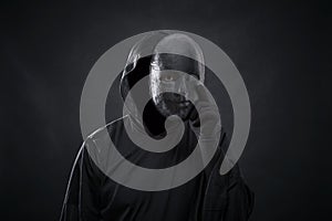 Scary figure in hooded cloak with mask in hand photo