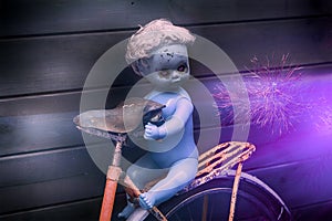 Scary ghost plastic doll with black tears at bicycle on mystic night nature background