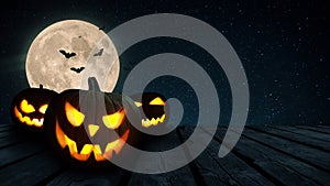 Scary glowing pumpkins on a wooden table on a background of a full moon with bats at night. Halloween and holiday wallpaper