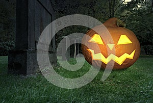 A scary grinning halloween pumpkin lies on a cemetery
