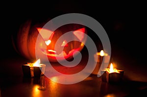 Scary halloween pumpkin and melon jack-o-lanterns on black background lit with small round and star candles