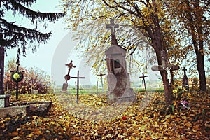 Scary leaning cross tomb stones in a foggy autumn scene in fall. Old creepy graves on cemetery in Slovakia. Spooky aged tombstones