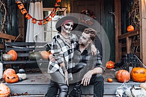 Scary love family couple man,woman celebrating halloween.Terrifying black skull half-face makeup,witch costumes.Stylish