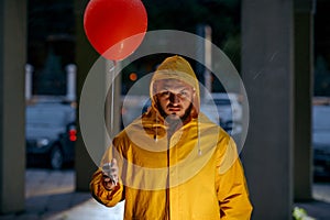 Scary man with balloon walking in night park