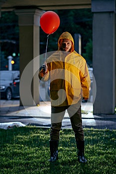 Scary man with balloon walking in night park