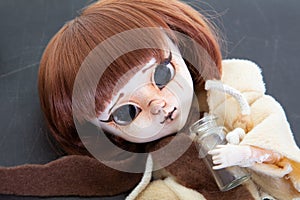 Scary plastic redhead doll with scarf lying on dark gray background