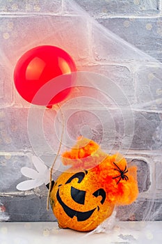 Scary red hair clown made from pumpkin, holding red balloon