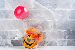 Scary red hair clown made from pumpkin, holding red balloon