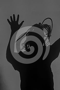 Scary silhouette of crying person with clotted hair, terrifying shadow on dark wall or behind mirror. Horror, nightmare photo