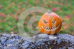 Scary smiling halloween pumpkin with nasty face on a stone