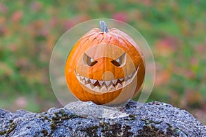 Scary smiling halloween pumpkin with nasty face on a stone