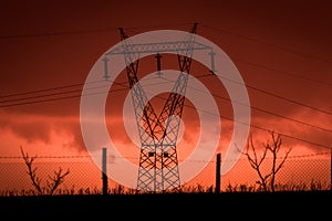 Scary sunset, with red sky and clouds, after storm. Power pylons and industrial fences in devastated landscape. B Evil environment