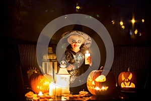 Scary toddler child in halloween costume, playing with carved pumpkins