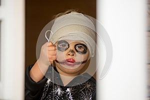 Scary toddler child in halloween costume, playing with carved pumpkins