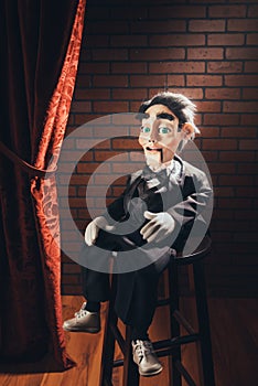 Scary ventriloquist doll sitting on a stool