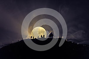 Scary view crowd of zombies on hill with spooky cloudy sky with fog and rising full moon. Silhouette group of zombie walking under