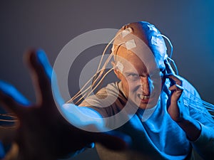 A scary young man with his head entangled in wires, uses mind control