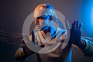 A scary young man with his head entangled in wires, uses mind control