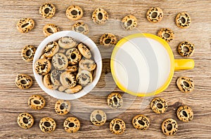 Scattered bread rings with poppy seeds, cup of milk