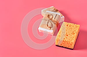 Scattered bricks of soap in vintage packing near sponge on pink background