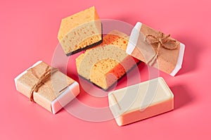 Scattered bricks of soap in vintage packing near sponges on pink background