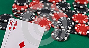 Scattered chips for betting in the casino and two game cards with a face value of 21, on the background of the green table
