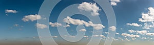 Scattered clouds across blue sky panorama