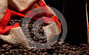 scattered coffee beans in a jute bag on a wooden background