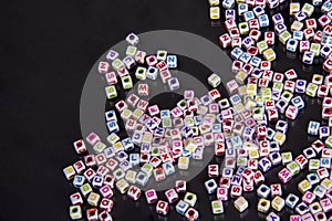 Scattered colorful kids alphabet beads on a black background