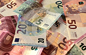 Scattered euro banknotes in denominations of five euros, ten euros, twenty euros, fifty euros, mixed banknotes as background