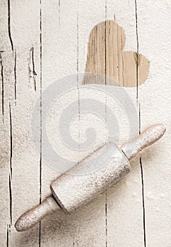 Scattered flour on an old wooden rolling pin