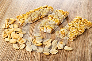 Scattered fried peanuts, pieces of kozinak on wooden table