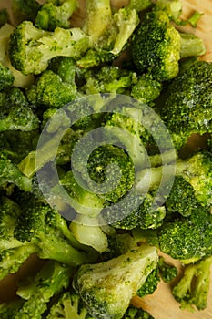 Scattered frozen broccoli on a wooden board.