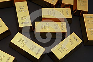 Scattered gold bars on the black table. Shiny precious metals for investments or reserves.