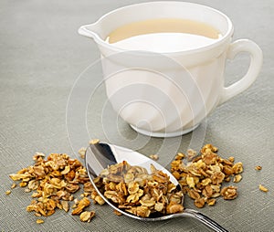 Scattered granola, spoon, yogurt in pitcher on table