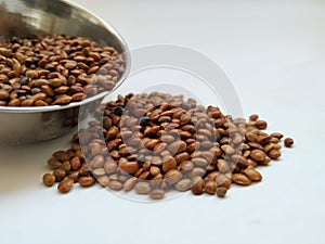 Scattered Horse Gram seeds from Steel Cup isolated on white background