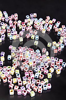 Scattered jewelry alphabet beads on a black background