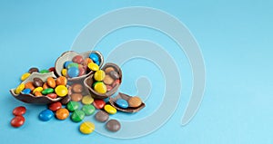 Scattered multi-colored candies in broken Chocolate Easter eggs on blue background
