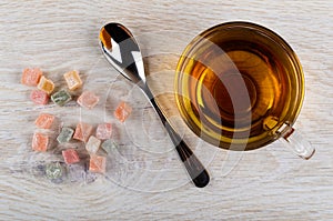 Scattered rakhat-lukum, cup of tea, teaspoon on table. Top view photo