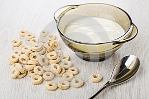 Scattered oat flakes, spoon, bowl with yogurt on table