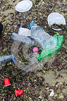 scattered plastic bottles, cups and mixed waste lying on the polluted beach