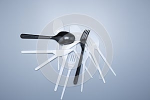 Scattered plastic forks knives spoons on a gray background close-up
