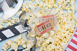 scattered popcorn on a blue background, a film and two tickets