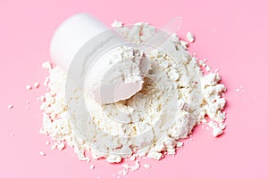 Scattered protein and measuring spoon on pink background top view