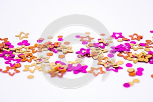 Scattered round confetti and in the form of flowers pink, gold and orange color on a white background. Copy space. Spring and