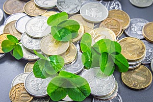 Scattered Russian coins on a gray background with leaves of clover. Good luck, St. Patrick's day.