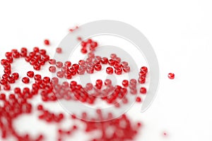 Scattered seed beads red color on a white surface