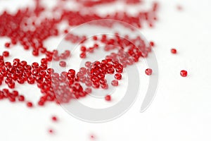 Scattered seed beads red color on a white surface